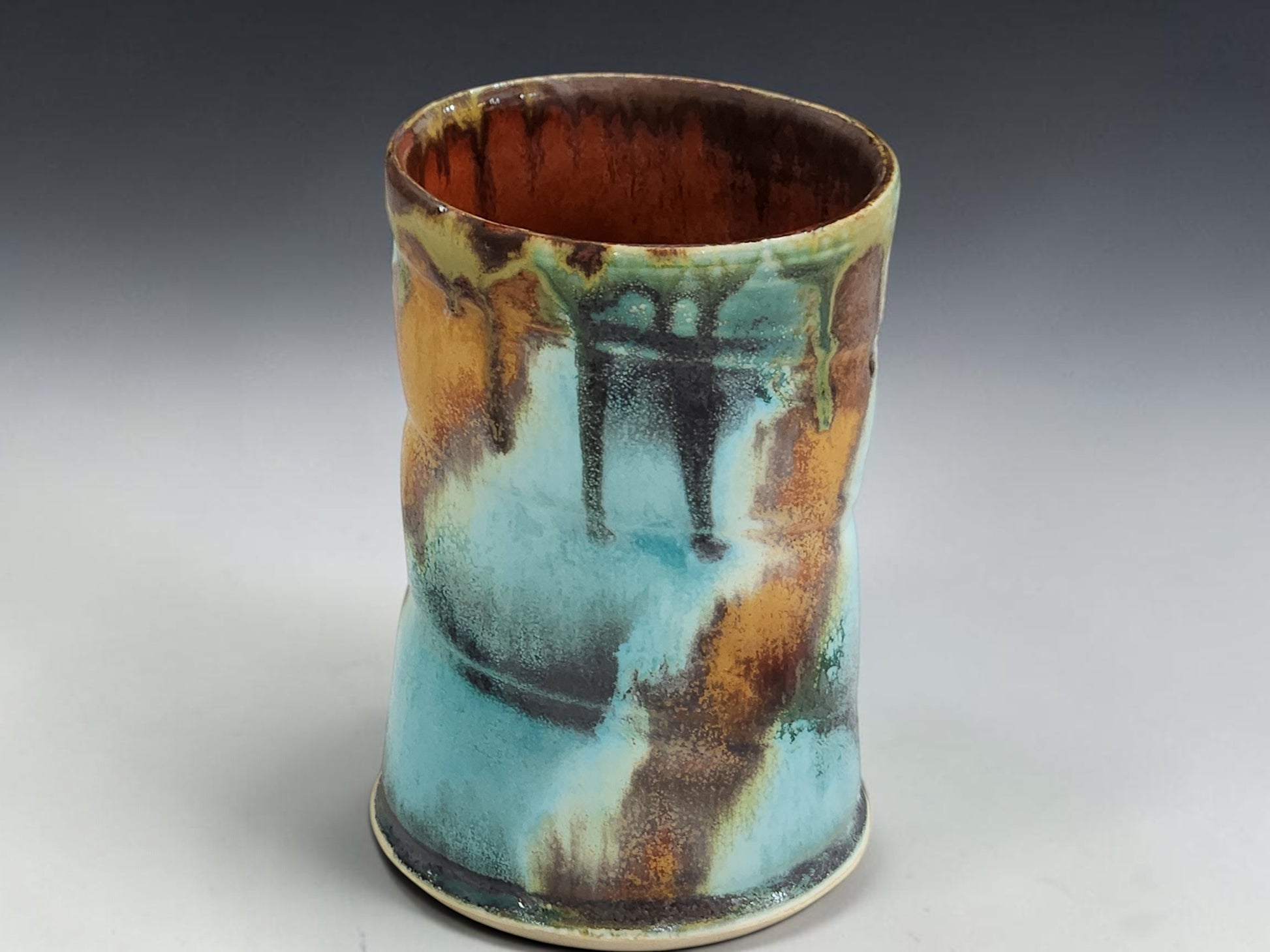 Handmade stoneware mug with flowing ash glaze drips and glossy red brown glazed interior