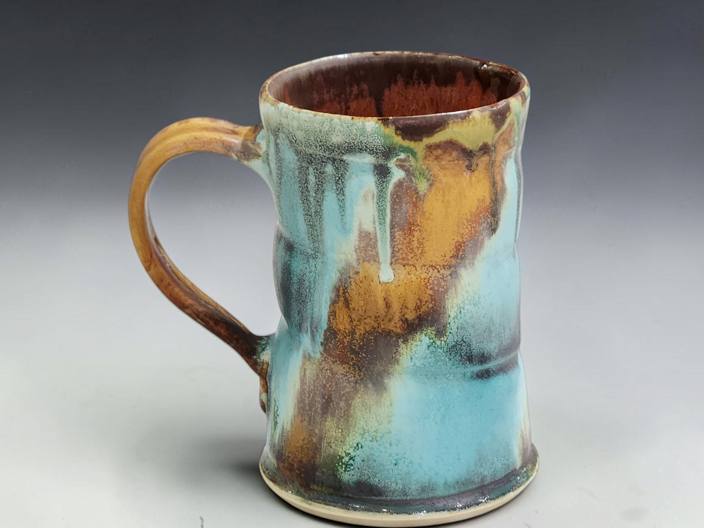 Australian handmade pottery mug with rustic turquoise, brown and rust glaze movement