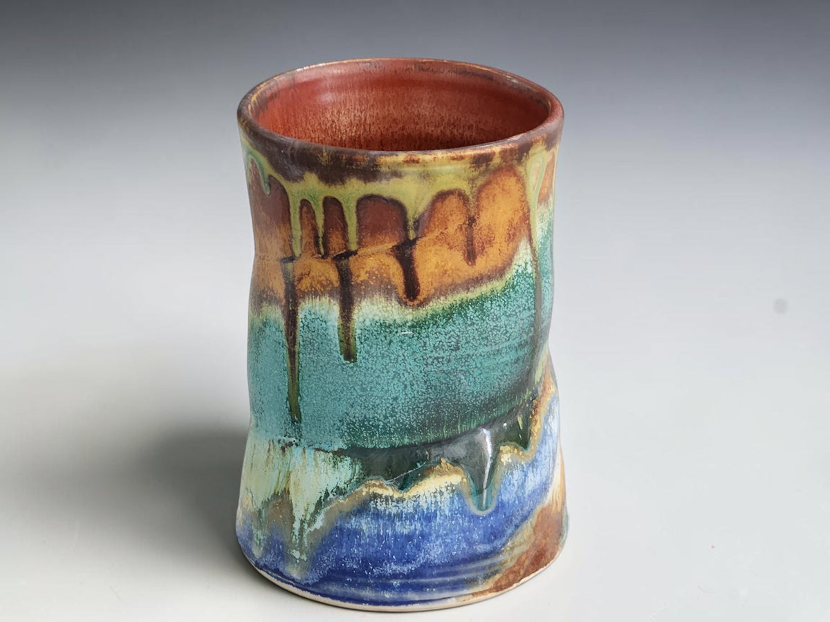 Handmade pottery mug with a curved brown handle and rust-brown interior.