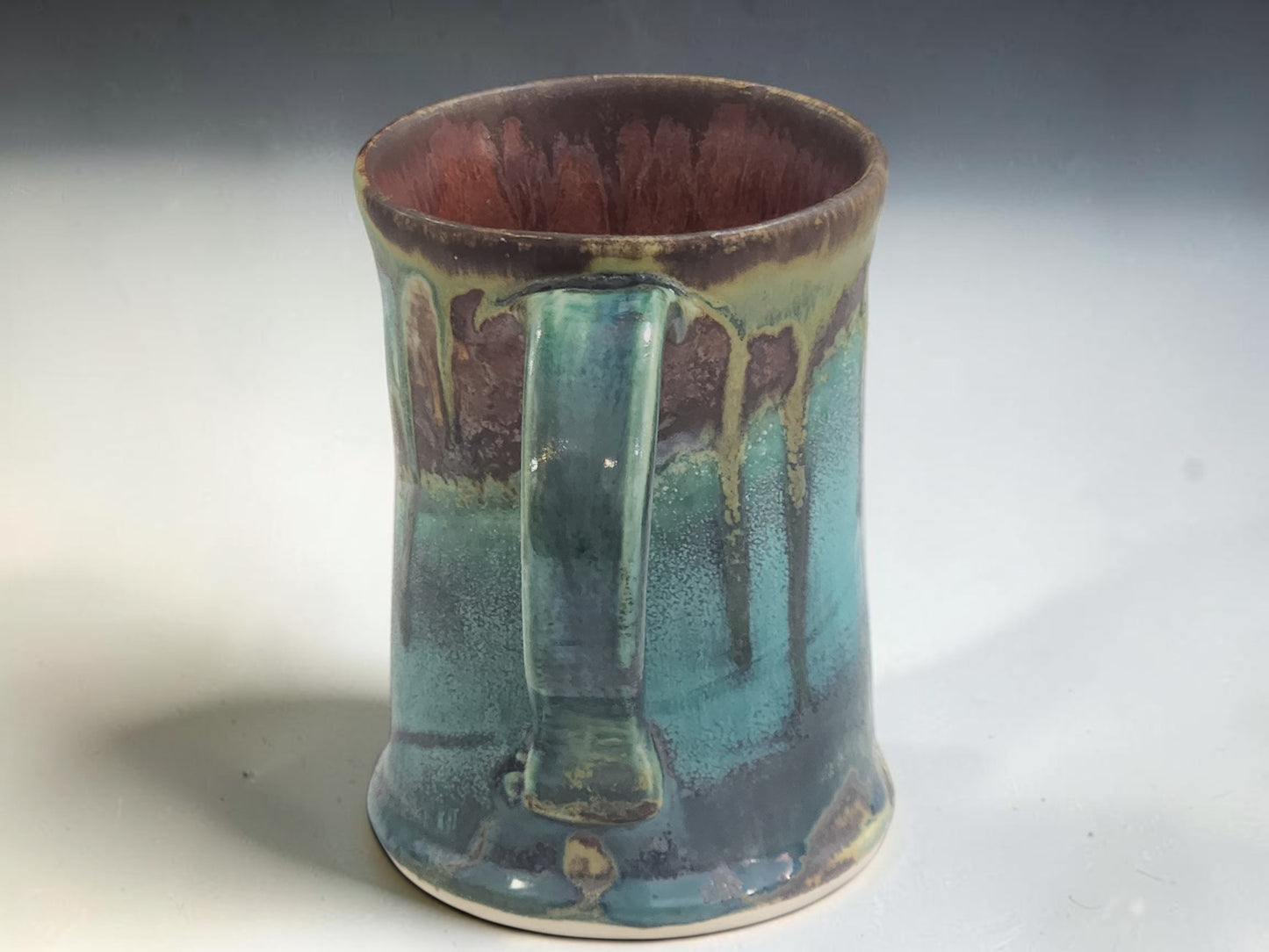 Tall Australian pottery mug with handcrafted flowing glaze in turquoise, green and earthy brown tones.