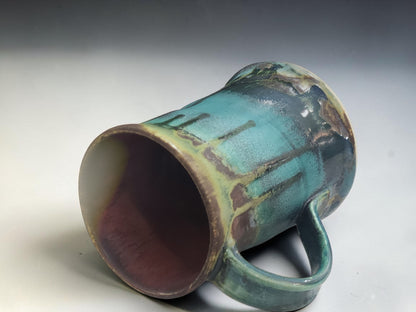 Side view of handmade Bush Creek Earth ceramic mug showing comfortable handle and cascading glaze movement.