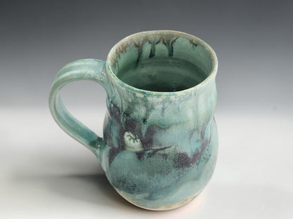 Wheel-thrown pottery mug with 450ml capacity, curved handle and glossy seafoam glaze on grey studio background
