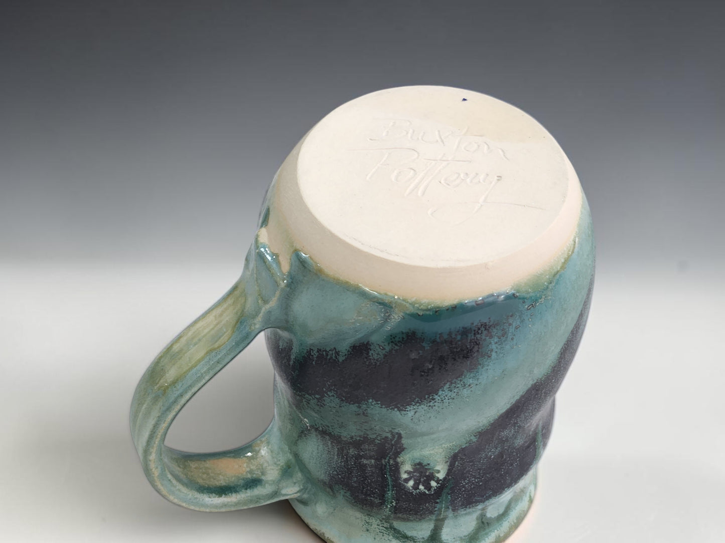 Handmade ceramic mug with rounded belly, glossy layered glaze and natural handmade variation on grey background