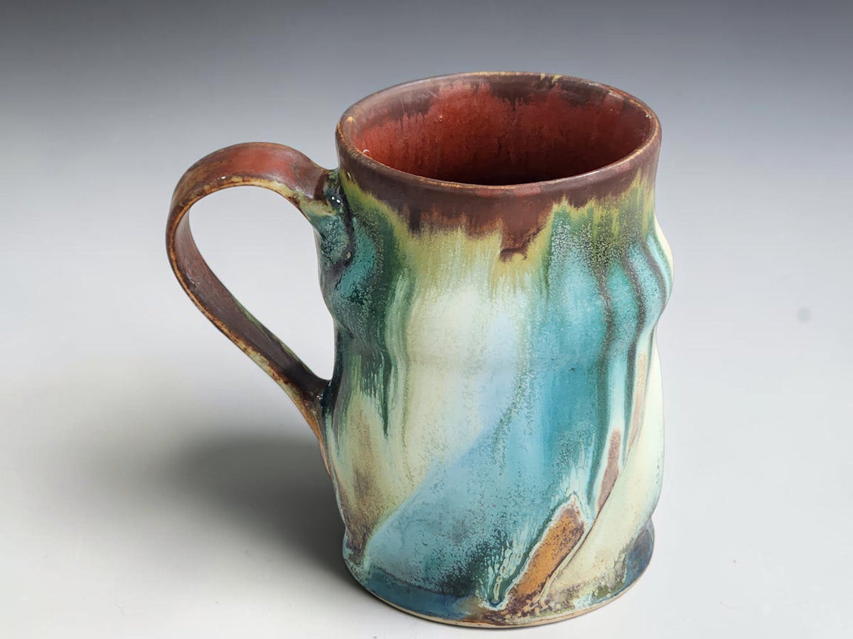 Handcrafted ceramic coffee mug with a brown rim and rust-brown interior.