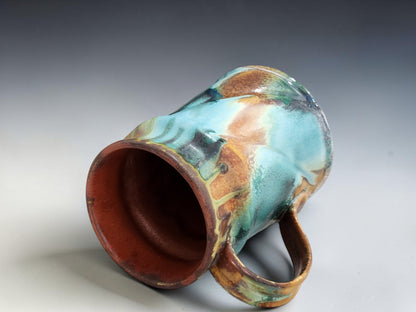 Handmade ceramic mug with curved handle, glossy layered glaze and natural handmade variation on grey background
