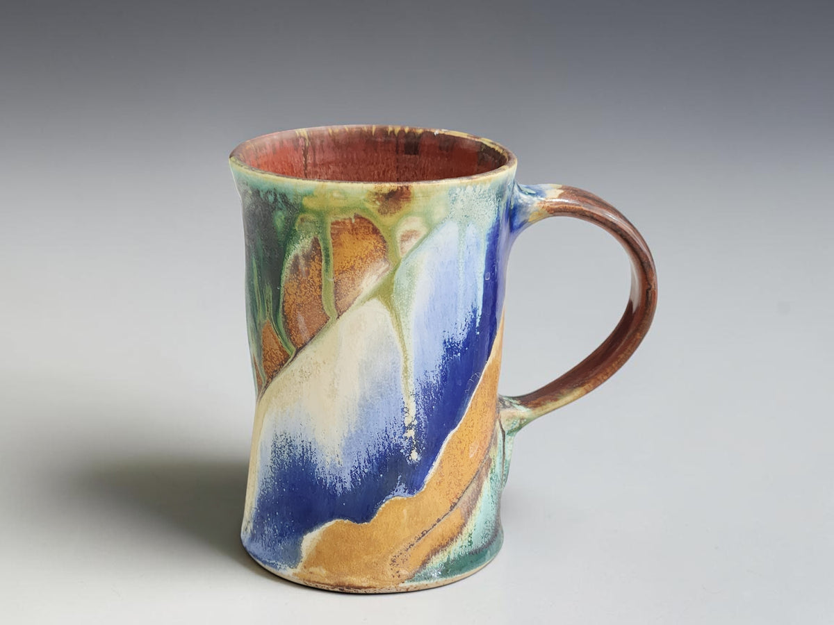 Handcrafted ceramic mug with a curved brown handle and terracotta-coloured interior.