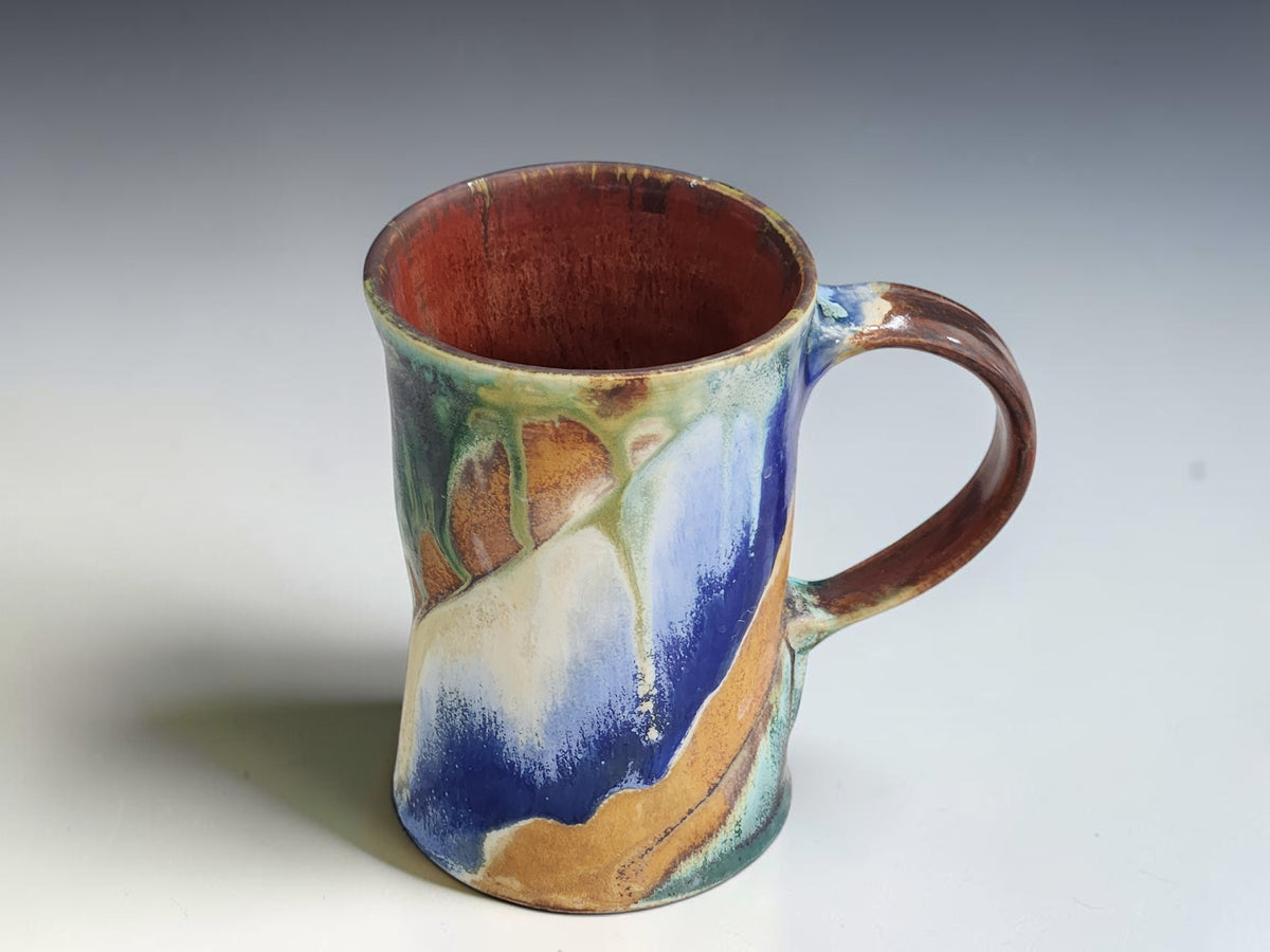 
Handmade Bush Creek 300ml ceramic mug by Buxton Pottery with blue, cream and earthy ochre glaze.
