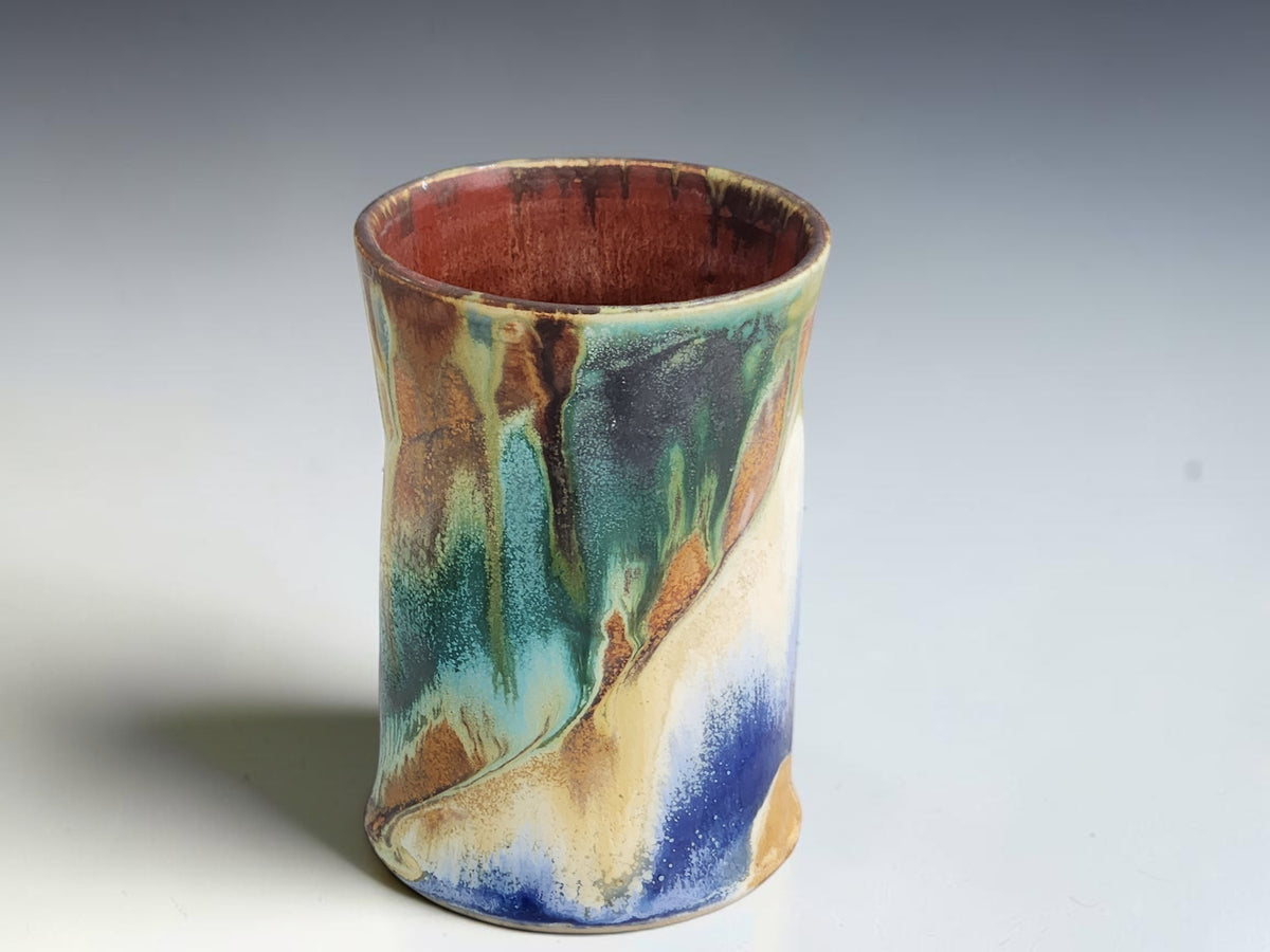 Tall handmade coffee mug with sweeping deep blue and pale cream glaze patterns.