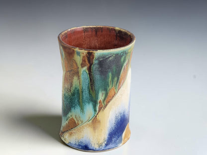 Tall handmade coffee mug with sweeping deep blue and pale cream glaze patterns.