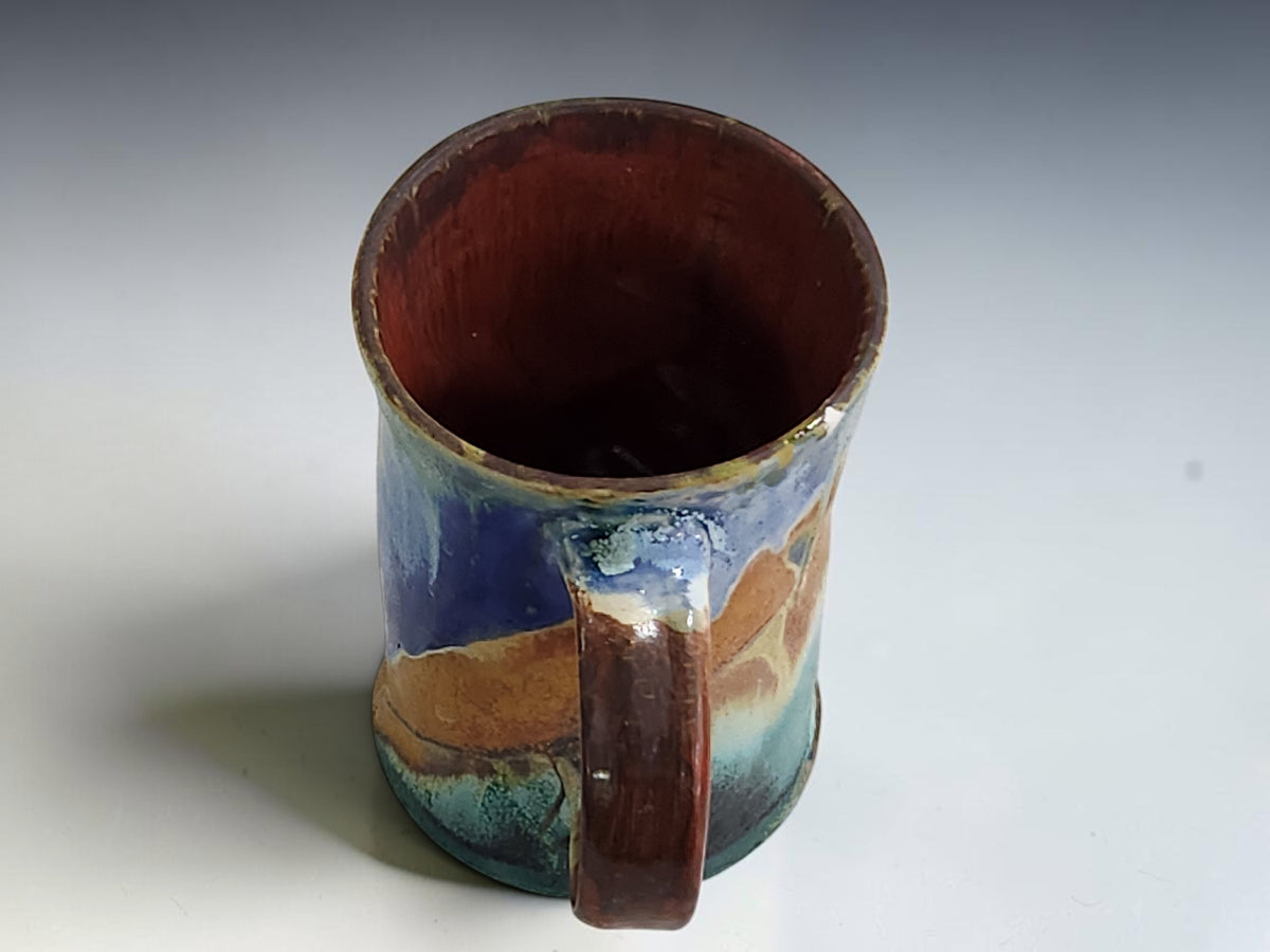 Blue and cream ceramic mug with a gently flared rim and subtly waisted shape.