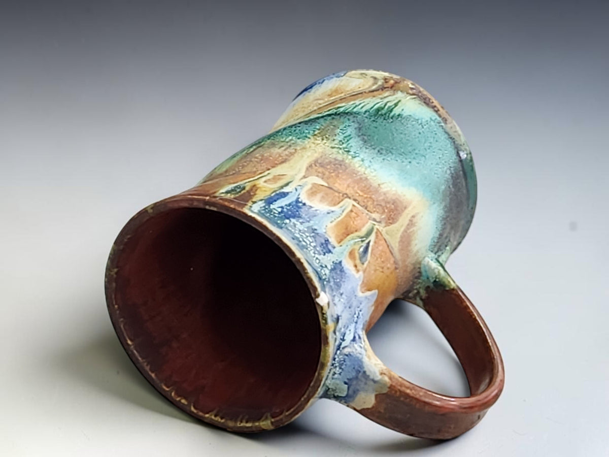 Ceramic coffee mug featuring a broad blue glaze sweep and earthy ochre band around the base.