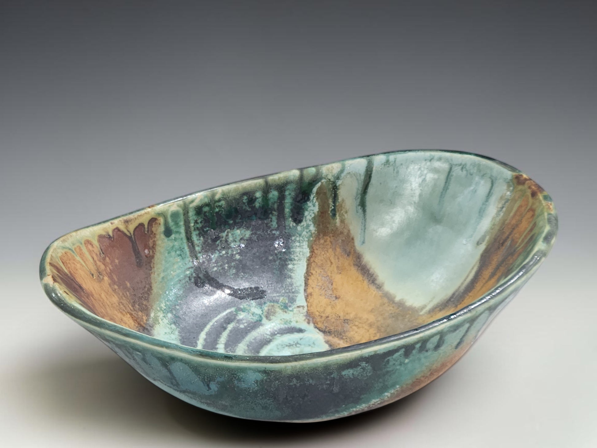 Wheel-thrown and altered ceramic bowl with hand-shaped oval form and glossy glaze variation
