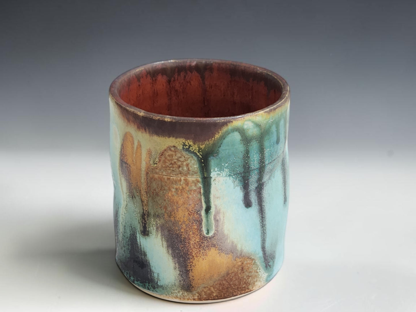 Handmade stoneware tumbler with straight-sided shape and rich organic glaze movement