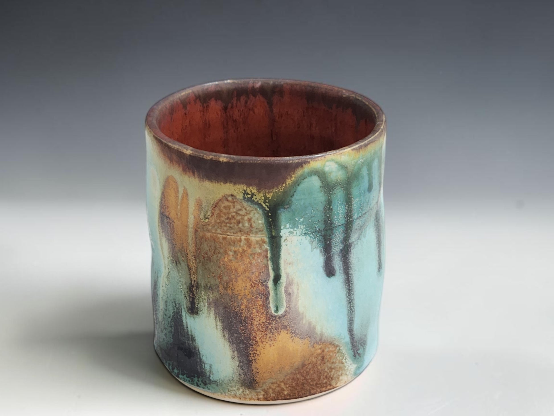 Handmade stoneware tumbler with straight-sided shape and rich organic glaze movement