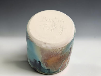 Handmade stoneware cup on grey studio background showing compact form and layered Bush Creek glaze