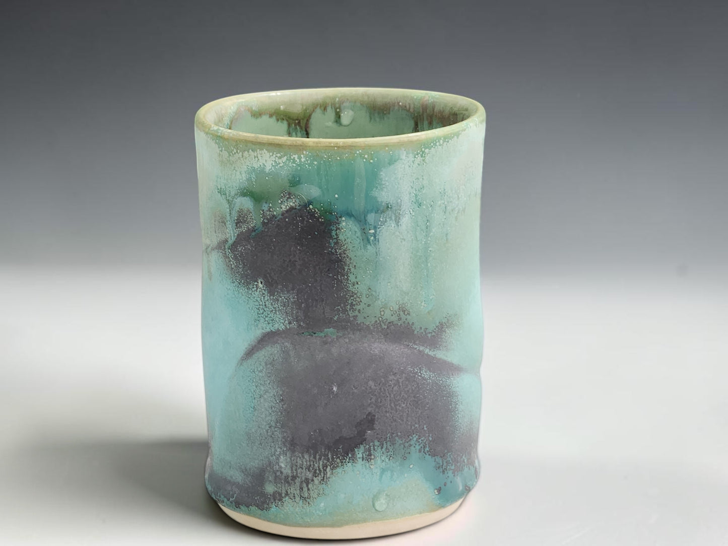 Handmade ceramic cup with soft seafoam green glaze and darker earthy glaze markings