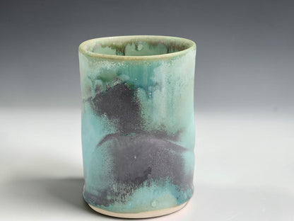 Handmade ceramic cup with soft seafoam green glaze and darker earthy glaze markings