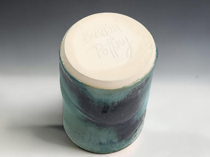 Handmade pottery tumbler on grey studio background showing compact shape and layered turquoise green glaze