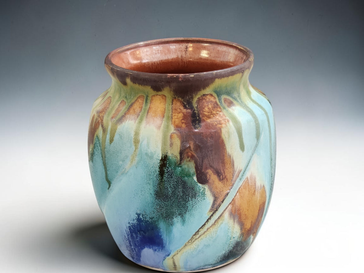 Side view of handmade stoneware vase with layered flowing glaze