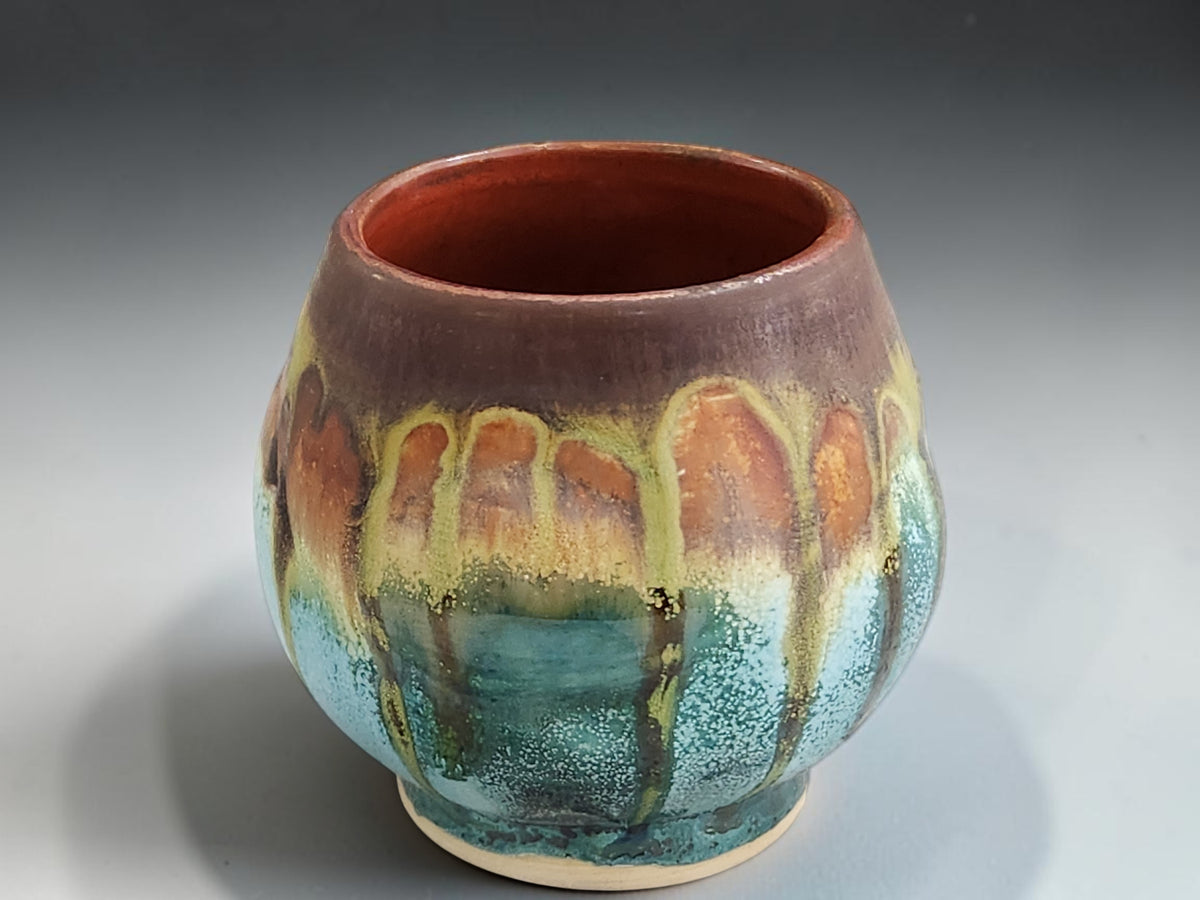 Handmade stoneware tea cup with deep brown interior and teal belly