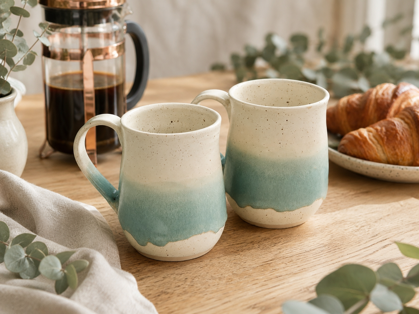 Handmade ceramic mugs by Buxton Pottery in a warm breakfast setting with French press coffee and croissant, featuring a soft green glaze band over speckled stoneware, handcrafted in Melbourne, Australia.