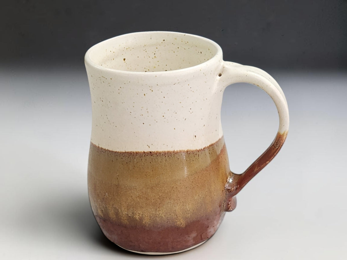 Tall handmade coffee mug with golden-brown and red-brown layered glaze
