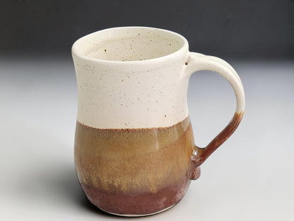 Tall handmade coffee mug with golden-brown and red-brown layered glaze