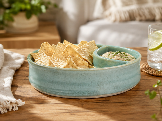 Handmade ceramic chip and dip bowl in spearmint green glaze styled with chips and dip in a relaxed kitchen setting