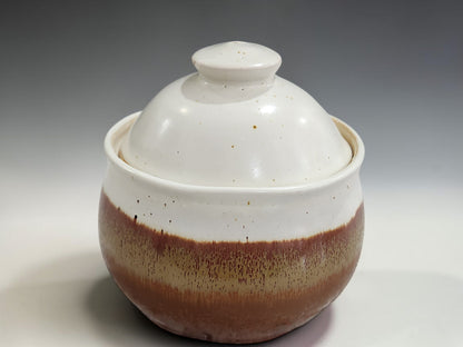 Round ceramic sugar pot with domed lid and speckled glaze detail, isolated on a professional grey gradient studio backdrop.