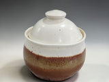 Round ceramic sugar pot with domed lid and speckled glaze detail, isolated on a professional grey gradient studio backdrop.