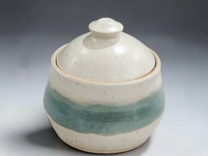 Speckled cream pottery sugar bowl with seafoam green glaze band and fitted ceramic lid