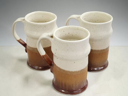 Set of three tall handmade pottery steins with speckled glaze and curved handles