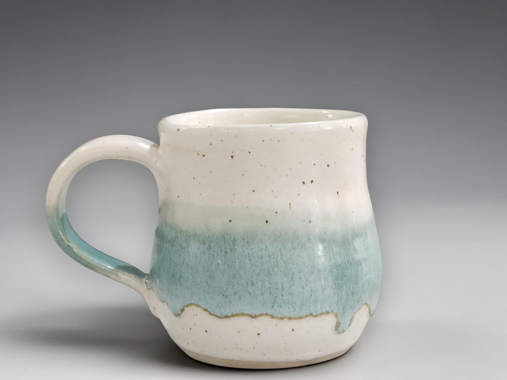 Handmade pottery mug in speckled cream and green glaze