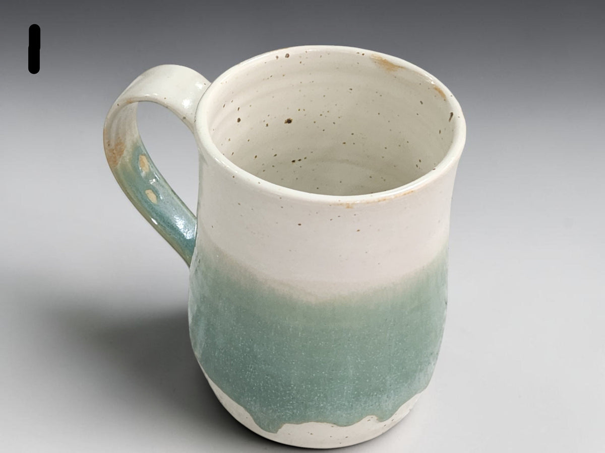 Tall pottery mug with cream top and green glazed base