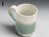 Tall pottery mug with cream top and green glazed base