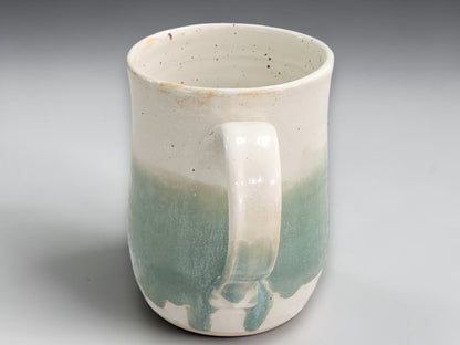 Handmade tea mug with soft green glaze and curved handle