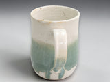 Handmade tea mug with soft green glaze and curved handle