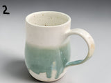 Handmade pottery cup with glossy green glaze detail