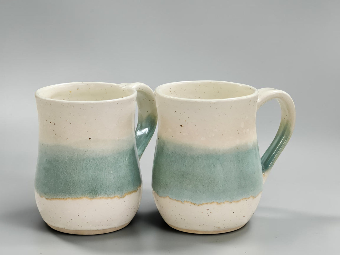 Handmade stoneware coffee mug with soft green glaze and speckled cream finish, crafted by Buxton Pottery in Melbourne for everyday coffee and tea enjoyment.