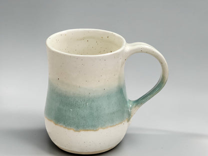 Handmade ceramic coffee mug with green and cream glaze combination, showcasing contemporary Australian pottery craftsmanship.