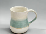 Handmade ceramic coffee mug with green and cream glaze combination, showcasing contemporary Australian pottery craftsmanship.
