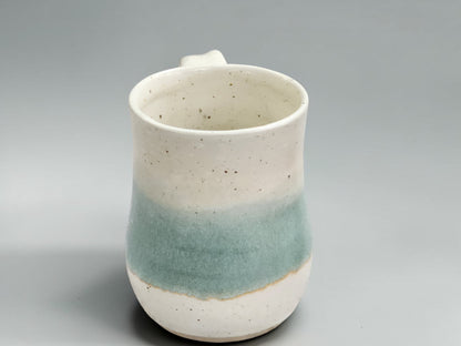 Australian handmade pottery mug featuring a soft green glaze over speckled stoneware clay, designed for coffee, tea and hot chocolate.