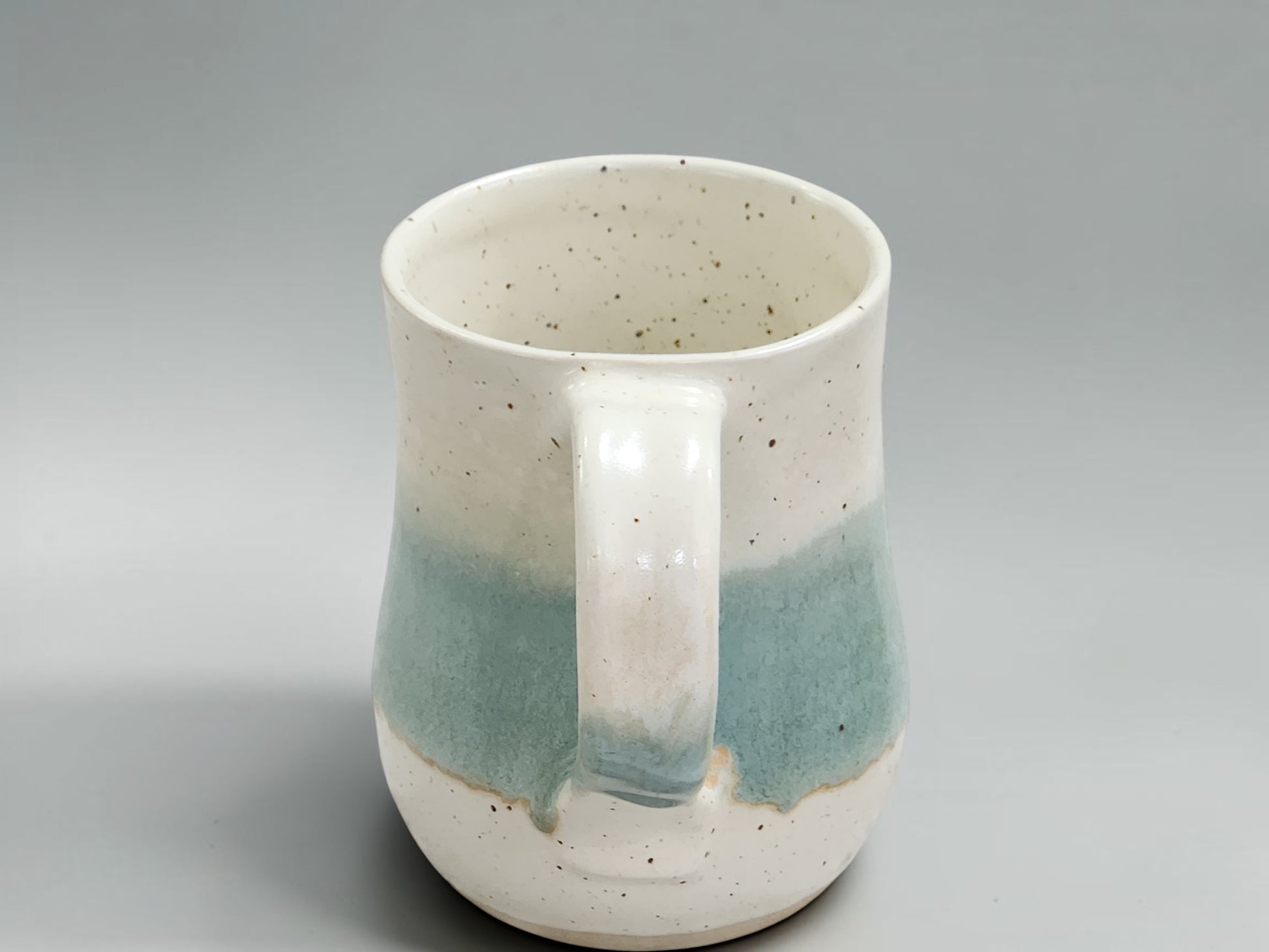 Handmade ceramic mug showcasing natural glaze movement and speckled stoneware texture, ideal for daily use and gifting.