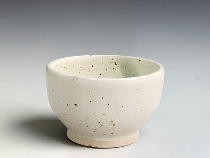 Handmade ceramic condiment bowl by Buxton Pottery with speckled cream glaze and a blue-green interior stripe.
