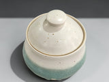 Handmade ceramic sugar bowl filled with sugar on a timber bench
