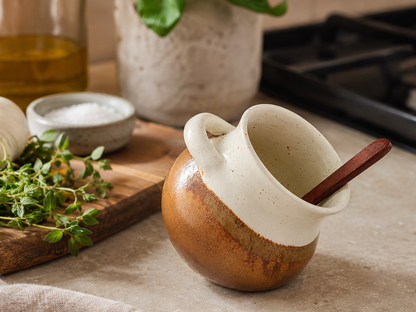 Handmade ceramic salt pig in cream and terracotta glaze styled in a warm kitchen setting with herbs and wooden spoon