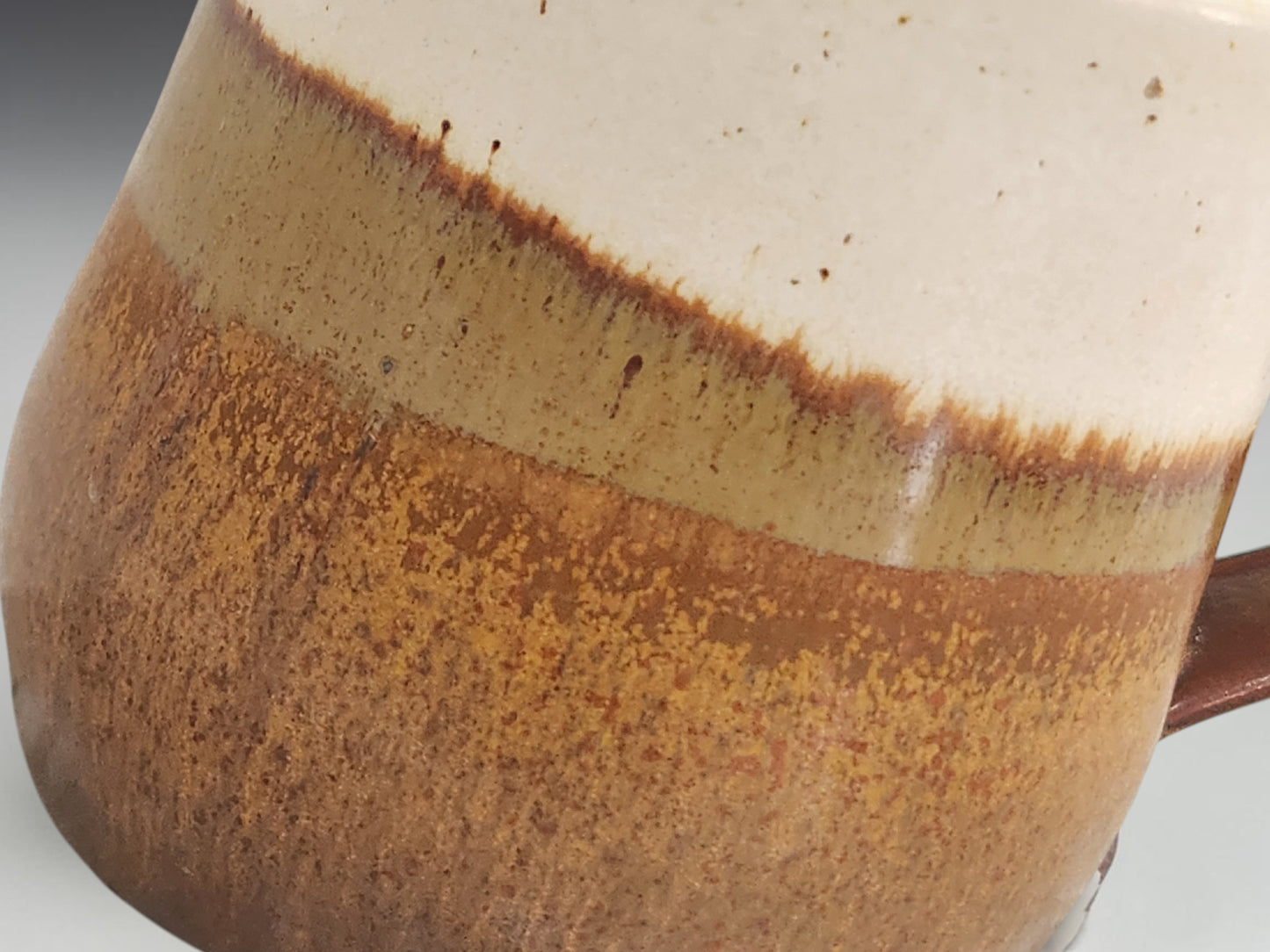 Close-up of warm brown and cream glaze on a handmade pottery mug