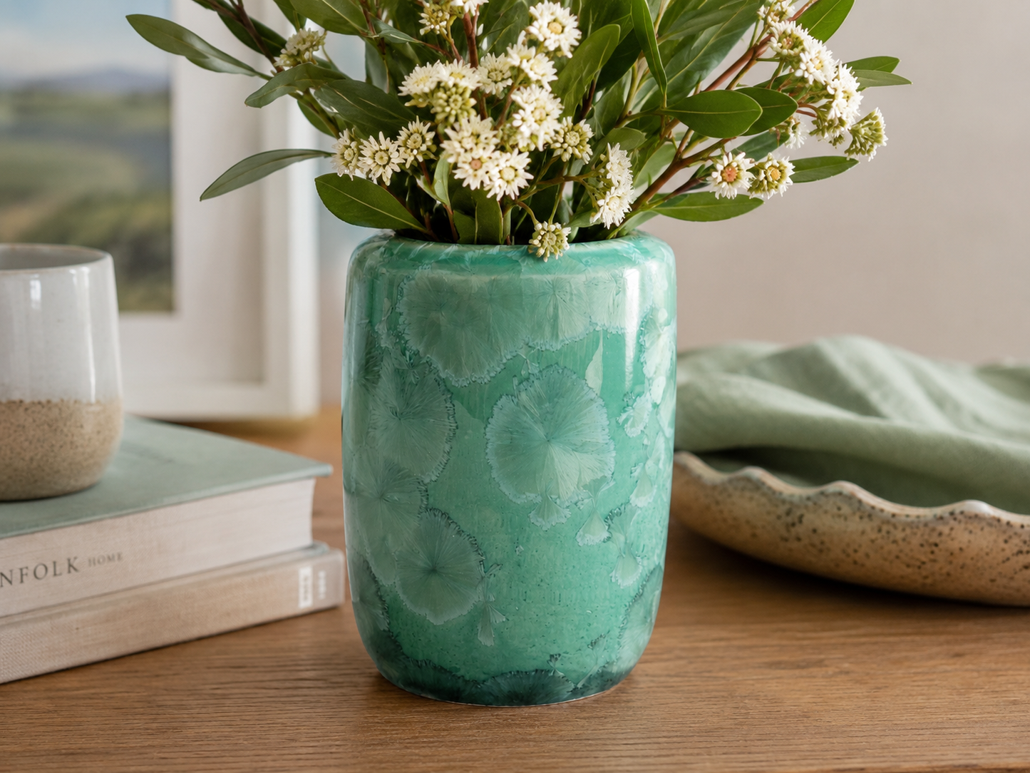 Green crystalline porcelain vase with white flowers in a lifestyle setting