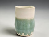 Tall pottery mug with cream top and green glazed base