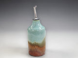 Handmade ceramic oil bottle with soft green and earthy brown glaze